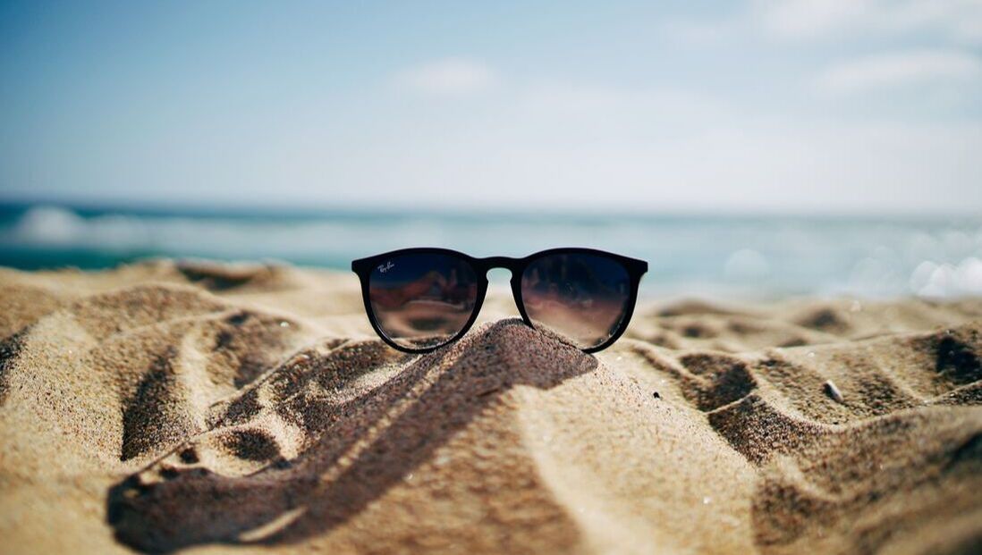 Zonnige dag op het strand met een zonnebril in het strand zand
